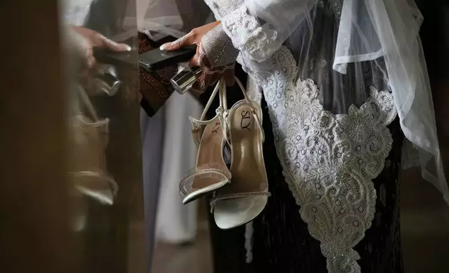 A bride holds her footwear during a mass wedding ceremony at Istiqlal Mosque in Jakarta, Indonesia, Wednesday, Dec. 3, 2025. (AP Photo/Tatan Syuflana)