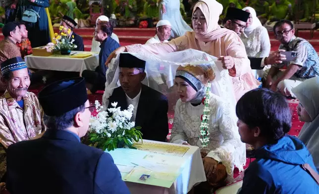 Fauzi, left, who uses only one name, and his bride Endah Kartini take part in a mass wedding ceremony at Istiqlal Mosque in Jakarta, Indonesia, Wednesday, Dec. 3, 2025. (AP Photo/Tatan Syuflana)