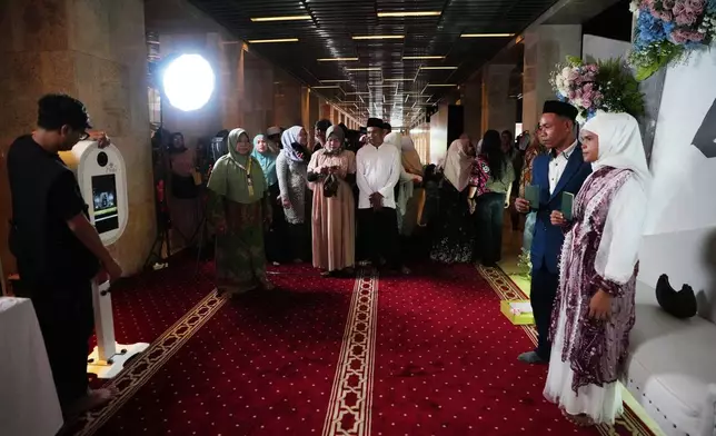 A bride and groom, right, have their photo taken after a mass wedding ceremony at Istiqlal Mosque in Jakarta, Indonesia, Wednesday, Dec. 3, 2025. (AP Photo/Tatan Syuflana)