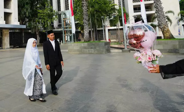 Dafa, second left, and his bride Zulfa arrive to take part in a mass wedding ceremony at Istiqlal Mosque in Jakarta, Indonesia, Wednesday, Dec. 3, 2025. (AP Photo/Tatan Syuflana)