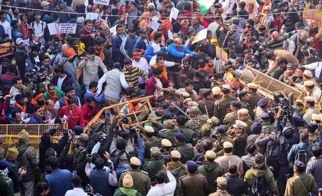 Police officers try to stop activists of Vishwa Hindu Parishad, a prominent right-wing Hindu nationalist organization, crossing over barricades during a protest near Bangladesh High Commission accusing Bangladeshi groups of wrongly targeting Indians, in New Delhi, India, Tuesday, Dec. 23, 2025. (AP Photo/Manish Swarup)