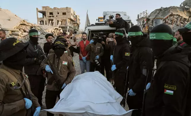 Masked Islamic Jihad and Hamas militants hand over a body bag believed to contain the remains of a deceased hostage to the Red Cross for transfer to Israeli authorities, in Beit Lahiya, in the northern Gaza Strip, Wednesday, Dec. 3, 2025. (AP Photo/Jehad Alshrafi)