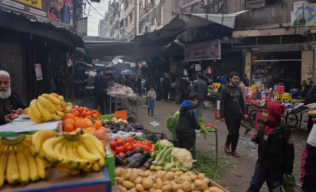 Palestinians walk along street market where fruits and vegetables are displayed for sale in Gaza City, Friday, Dec. 19, 2025. (AP Photo/Abdel Kareem Hana)