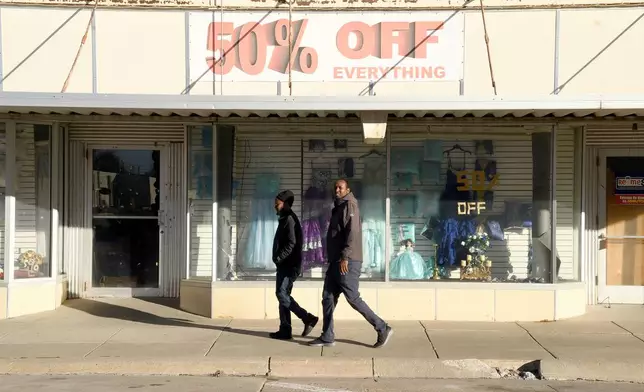 Two men walk past a business in downtown Lexington, Neb., Saturday, Dec. 6, 2025. (AP Photo/Thomas Peipert)