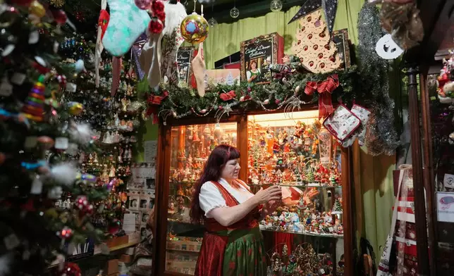 Owner of the Christel Dauwe Collection ornaments shop, Christel Dauwe, takes a holiday ornament out of a display case at her shop in Antwerp, Belgium, Monday, Dec. 8, 2025. (AP Photo/Virginia Mayo)