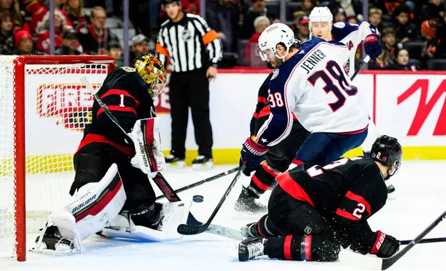 Columbus Blue Jackets' Boone Jenner (38) attempts to deflect a shot past Ottawa Senators' goaltender Leevi Merilainen (1) during the first period of an NHL hockey game, in Ottawa, Ontario, Monday, Dec. 29, 2025. (Spencer Colby/The Canadian Press via AP)
