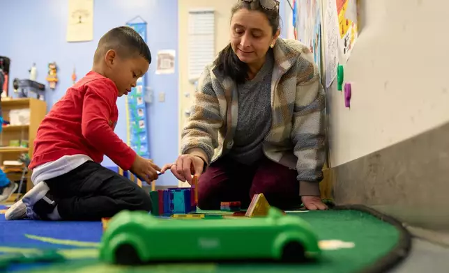 Belkis Mendez, builds with a Prek-5 student during playtime in their classroom at CentroNia in Washington, Tuesday, Dec. 9, 2025. (AP Photo/Jacquelyn Martin)