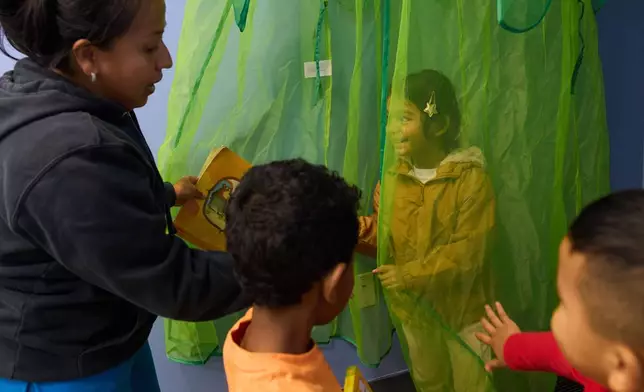 Celenia Romero reads to her Prek-5 students as they play in the library at CentroNia in Washington, Tuesday, Dec. 9, 2025. (AP Photo/Jacquelyn Martin)