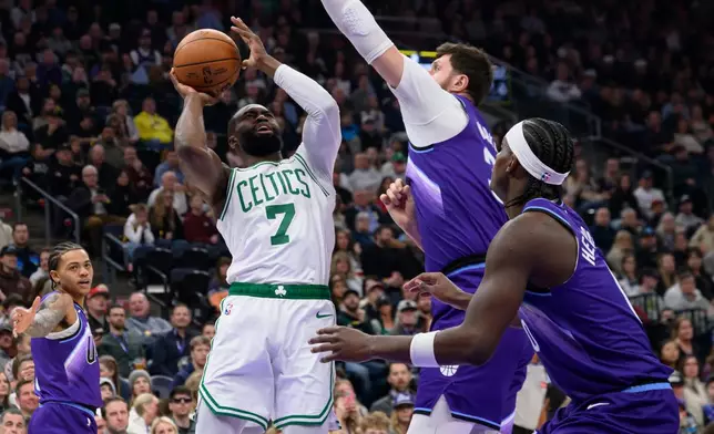 Boston Celtics guard Jaylen Brown, center left, shoots around the defense of Utah Jazz center Jusuf Nurkic, center right, during the first half of an NBA basketball game, Tuesday, Dec. 30, 2025, in Salt Lake City. (AP Photo/Tyler Tate)