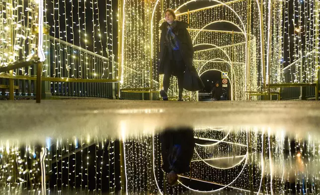 FILE - A woman walks across a bridge decorated prior to Christmas and New Year festivities in St. Petersburg, Russia, Thursday, Dec. 11, 2025. (AP Photo/Dmitri Lovetsky, File)
