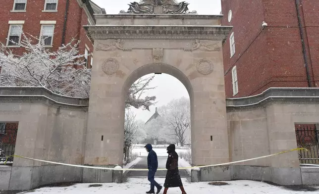 Passers-by walk past crime scene tape at an entrance to Brown University, Sunday, Dec. 14, 2025, in Providence, R.I., following the Saturday, Dec. 13, shooting at the university. (AP Photo/Steven Senne)