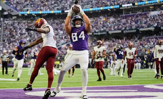 Minnesota Vikings tight end Josh Oliver (84) celebrates next to Washington Commanders cornerback Jonathan Jones after scoring a touchdown during the second half of an NFL football game, Sunday, Dec. 7, 2025, in Minneapolis. (AP Photo/Abbie Parr)