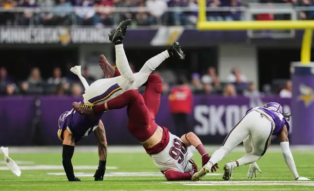 Washington Commanders tight end Zach Ertz (86) hits the ground after not being able to catch a pass between Minnesota Vikings linebacker Blake Cashman, left, and safety Jay Ward during the second half of an NFL football game, Sunday, Dec. 7, 2025, in Minneapolis. (AP Photo/Abbie Parr)