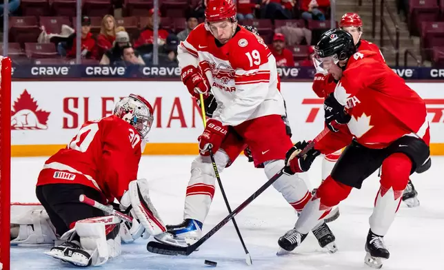 Canada goaltender Carter George (30) and Harrison Brunicke (4) defend against Denmark's William Bundgaard (19) in front of the net during the second period of an IIHF World Junior Championship hockey game in Minneapolis, Monday, Dec. 29, 2025. (Christopher Katsarov/The Canadian Press via AP)
