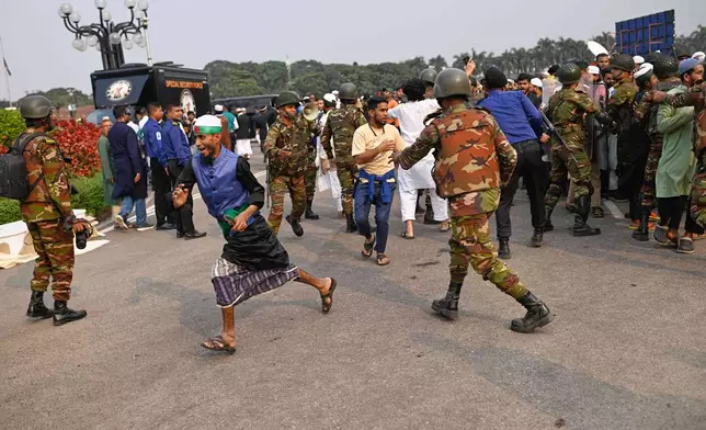Security forces control a group of people who arrived to participate in the funeral prayers for leading Bangladeshi activist Sharif Osman Hadi, who died from gunshot wounds sustained in an attack in Dhaka earlier this month, in Dhaka, outside the nation's Parliament complex in Dhaka, Bangladesh, Saturday, Dec. 20, 2025. (AP Photo/Mahmud Hossain Opu)