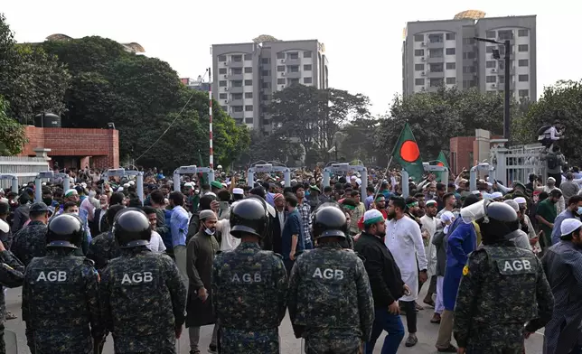 Security forces stand guard at the entrance of nation's Parliament complex as people arrive to perform funeral prayers for leading Bangladeshi activist Sharif Osman Hadi, who died from gunshot wounds sustained in an attack in Dhaka earlier this month, in Dhaka, Bangladesh, Saturday, Dec. 20, 2025. (AP Photo/Mahmud Hossain Opu)