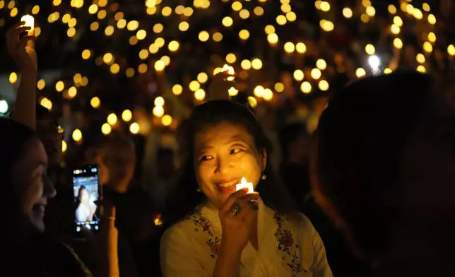 A worshiper holds an electric candle during a Christmas Eve service at Indonesia Arena stadium in Jakarta, Indonesia, Wednesday, Dec. 24, 2025. (AP Photo/Tatan Syuflana)