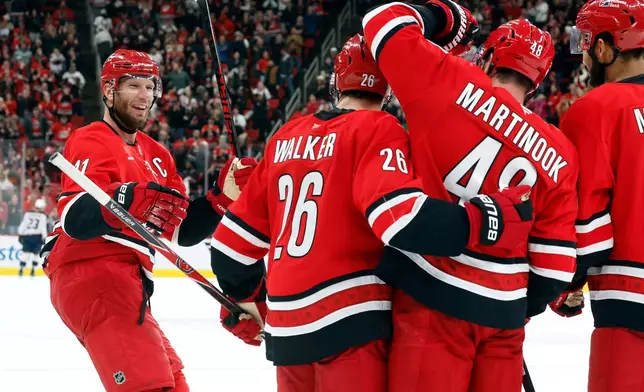 Carolina Hurricanes' Jordan Staal (11) joins the celebration on an empty net goal by Jordan Martinook (48) with Sean Walker (26) and K'Andre Miller (19) nearby during the third period of an NHL hockey game against the Columbus Blue Jackets in Raleigh, N.C., Tuesday, Dec. 9, 2025. (AP Photo/Karl DeBlaker)