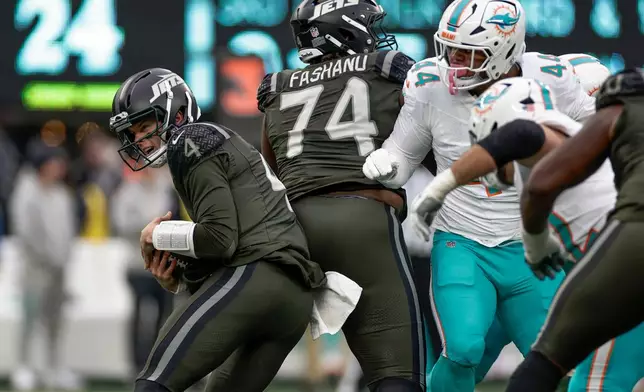 New York Jets quarterback Brady Cook (4) tucks the ball under pressure from the Miami Dolphins during the third quarter of an NFL football game, Sunday, Dec. 7, 2025, in East Rutherford, N.J. (AP Photo/Adam Hunger)