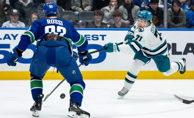 Vancouver Canucks' Marco Rossi (93) blocks a shot by San Jose Sharks' Macklin Celebrini (71) during the second period of an NHL hockey game in Vancouver, British Columbia, Saturday, Dec. 27, 2025. (Ethan Cairns/The Canadian Press via AP)