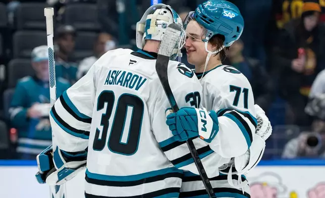 San Jose Sharks goaltender Yaroslav Askarov (30) and Macklin Celebrini (71) celebrate after defeating the Vancouver Canucks in an NHL hockey game in Vancouver, British Columbia, Saturday, Dec. 27, 2025. (Ethan Cairns/The Canadian Press via AP)