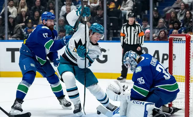Vancouver Canucks goaltender Thatcher Demko (35) stops San Jose Sharks' Macklin Celebrini (71) as Canucks' Filip Hronek (17) defends during the first period of an NHL hockey game in Vancouver, British Columbia, Saturday, Dec. 27, 2025. (Ethan Cairns/The Canadian Press via AP)
