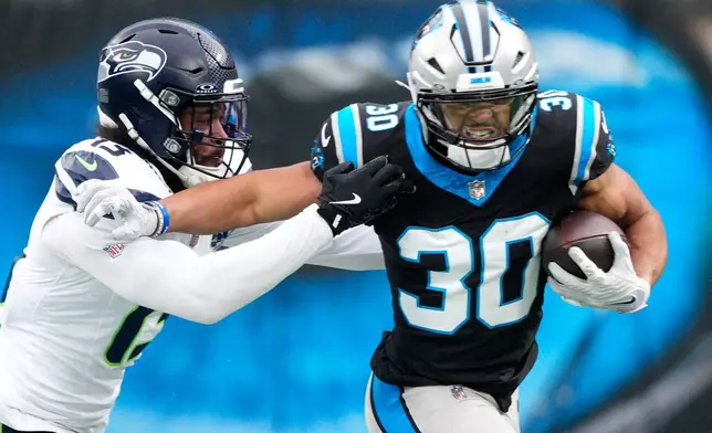 Carolina Panthers running back Chuba Hubbard pushes off Seattle Seahawks linebacker Ernest Jones IV during the first half of an NFL football game, Sunday, Dec. 28, 2025, in Charlotte, N.C. (AP Photo/Jacob Kupferman)