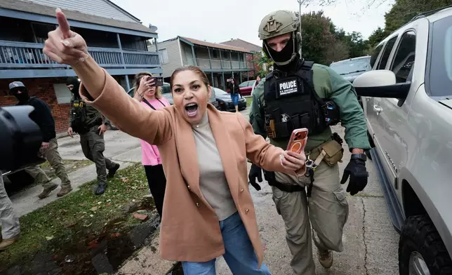 FILE - Wilma Fuentes yells at Customs and Border Patrol commander Gregory Bovino and some of his agents as they walk through a neighborhood during an immigration crackdown, in Kenner, La., Dec. 5, 2025. (AP Photo/Gerald Herbert, File)