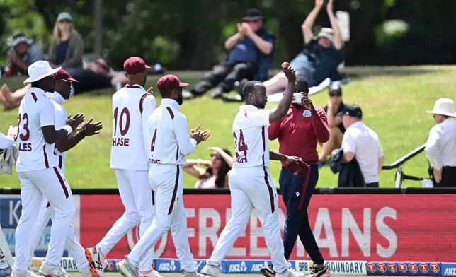 West Indies' Kemar Roach, right, holds up the ball after taking 5 wickets against New Zealand on Day 4 of their cricket test match in Christchurch, New Zealand, Friday, Dec. 5, 2025. (Andrew Cornaga/Photosport via AP)