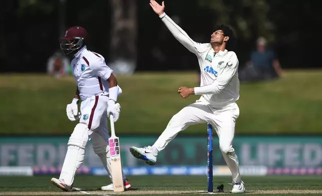 New Zealand's Rachin Ravindra, right, bowls as West Indies' Justin Greaves prepares to run on Day 4 of their cricket test match in Christchurch, New Zealand, Friday, Dec. 5, 2025. (Chris Symes/Photosport via AP)