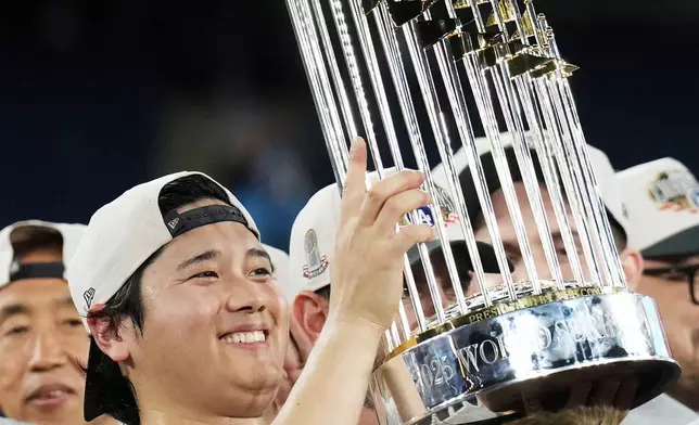 FILE - Los Angeles Dodgers pitcher Shohei Ohtani lifts the trophy as the Dodgers celebrate after defeating the Toronto Blue Jays in Game 7 of baseball's World Series, Sunday, Nov. 2, 2025, in Toronto. (Nathan Denette/The Canadian Press via AP, File)