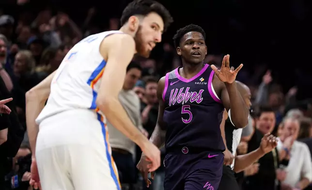 Minnesota Timberwolves guard Anthony Edwards, right, celebrates his three-point basket as Oklahoma City Thunder center Chet Holmgren, left, looks on during the first half of an NBA basketball game, Friday, Dec. 19, 2025, in Minneapolis. (AP Photo/Matt Krohn)