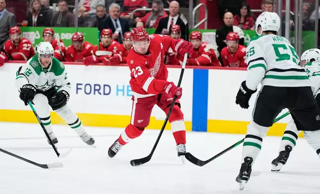 Detroit Red Wings left wing Lucas Raymond, center, shoots against Dallas Stars center Radek Faksa, left, and defenseman Thomas Harley during the second period of an NHL hockey game Tuesday, Dec. 23, 2025, in Detroit. (AP Photo/Ryan Sun)