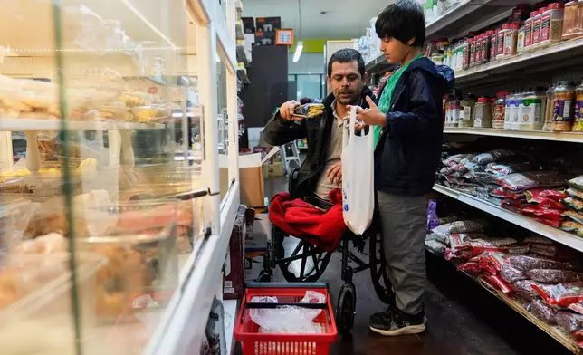 Abdul Salam, center, and his son Ahmad Sodais shop for sweet treats inside of an Afghan grocery store in Carmichael, Calif., Friday, Dec. 5, 2025. (AP Photo/Godofredo A. Vásquez)
