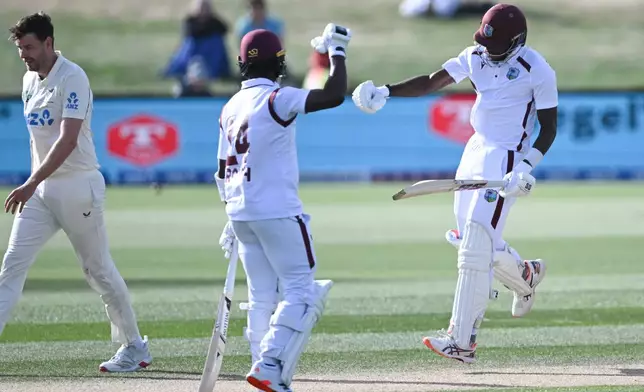 West Indies' Justin Greaves, right, celebrates with teammate Kemar Roach, center, after scoring 200 runs against New Zealand on Day 5 of their cricket test match in Christchurch, New Zealand, Saturday, Dec. 6, 2025. (Andrew Cornaga/Photosport via AP)
