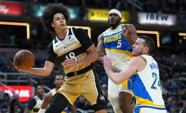 Washington Wizards forward Kyshawn George, left, passes around Indiana Pacers guard Garrison Mathews, right, during the first half of an NBA basketball game in Indianapolis, Sunday, Dec. 14, 2025. (AP Photo/AJ Mast)