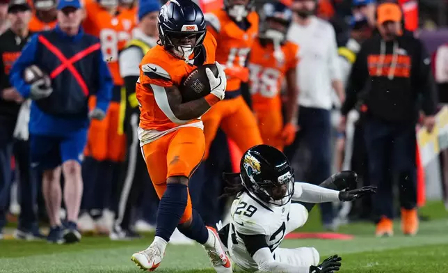 Denver Broncos running back RJ Harvey, left, runs against Jacksonville Jaguars safety Eric Murray (29) during the second half of an NFL football game in Denver, Sunday, Dec. 21, 2025. (AP Photo/Jack Dempsey)