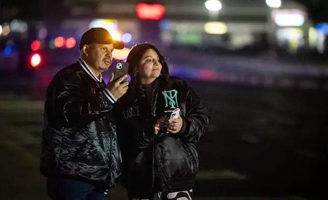 Bystanders watch at the scene of a mass shooting Saturday, Nov. 29, 2025, in Stockton, Calif. (AP Photo/Ethan Swope)