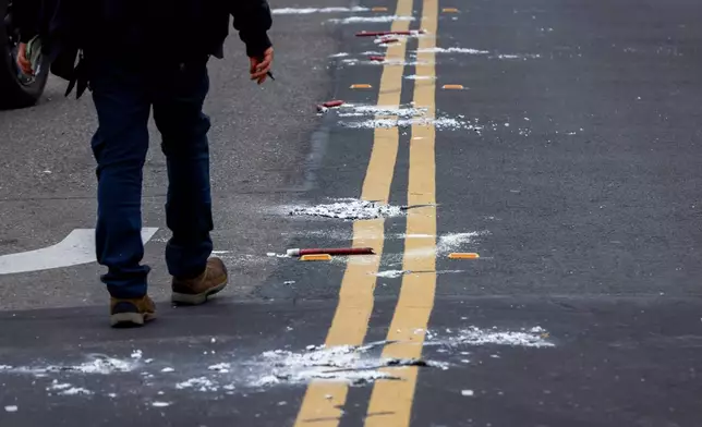 A man walks near the remains of flares as investigators with the San Joaquin Sheriff's Department work near the site of Saturday's shooting at a banquet hall in Stockton, Calif., Sunday, Nov. 30, 2025. (Brontë Wittpenn/San Francisco Chronicle via AP)