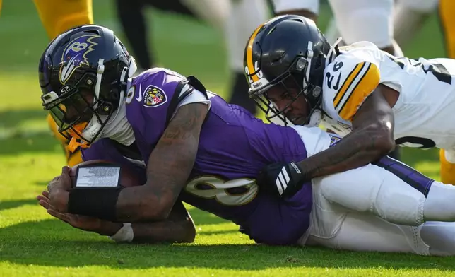 Pittsburgh Steelers cornerback Brandin Echols (26) tackles Baltimore Ravens quarterback Lamar Jackson (8) during the first half of an NFL football game, Sunday, Dec. 7, 2025, in Baltimore. (AP Photo/Stephanie Scarbrough)
