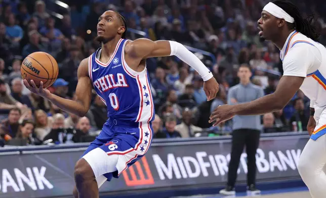 Philadelphia 76ers guard Tyrese Maxey (0) goes to the basket past Oklahoma City Thunder guard Luguentz Dort, right, during the first half of an NBA basketball game, Sunday, Dec. 28, 2025, in Oklahoma City. (AP Photo/Nate Billings)