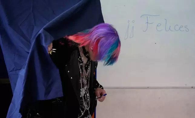 A voter leaves the booth where ballots are marked during the presidential runoff election in Santiago, Chile, Sunday, Dec. 14, 2025. (AP Photo/Matias Delacroix)