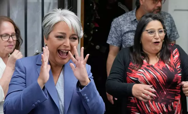 Presidential candidate Jeannette Jara, the ruling Unity for Chile coalition, greets neighbors before heading to vote at her parents' home in Santiago, Chile, Sunday, Dec. 14, 2025. (AP Photo/Natacha Pisarenko)
