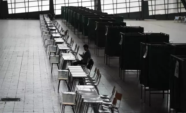 An electoral official sits at a polling station before polls opened for the presidential runoff election in Santiago, Chile, Sunday, Dec. 14, 2025. (AP Photo/Natacha Pisarenko)
