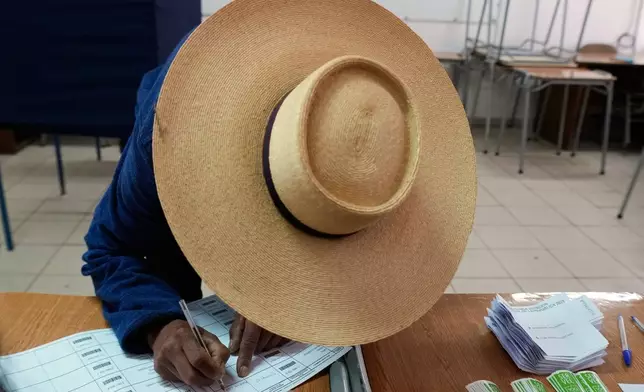 A voter signs the registry during the presidential runoff election in Santiago, Chile, Sunday, Dec. 14, 2025. (AP Photo/Esteban Felix)