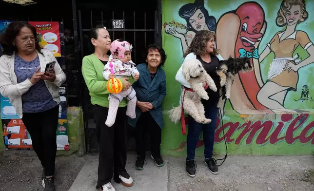 Neighbors watch Jeannette Jara, presidential candidate of the ruling Unity for Chile coalition, walk to vote for the presidential runoff election in Santiago, Chile, Sunday, Dec. 14, 2025. (AP Photo/Natacha Pisarenko)