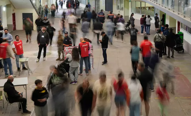 Voters walk at a polling station during the presidential runoff election in Santiago, Chile, Sunday, Dec. 14, 2025. (AP Photo/Matias Delacroix)