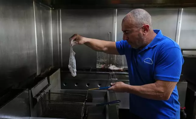 Stefanos Mentonis, owner of Stefanos restaurant, cooks lionfish in Larnaca, Cyprus, in the eastern Mediterranean, Thursday, Dec. 18, 2025. (AP Photo/Petros Karadjias)
