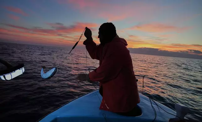 Fisherman Photis Gaitanos catches a toadfish while fishing from his boat off the coast of Larnaca, Cyprus, in the eastern Mediterranean, early Saturday, Dec. 20, 2025. (AP Photo/Petros Karadjias)
