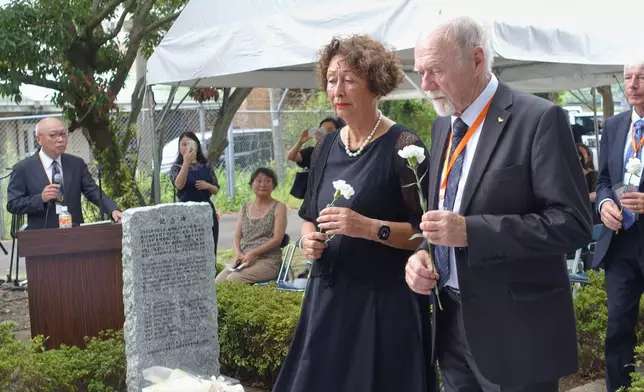 Andre Schram, right, the son of a former Dutch POW, lays a chrysanthemum flower to commemorate the victims at a memorial held at the former site of the Fukuoka No. 2 Camp in Koyagi, Nagasaki City, western Japan, Saturday, Sept. 13, 2025. (AP Photo/Mari Yamaguchi)